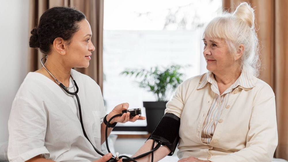 A female nurse checking the blood pressure in an ederly pacient