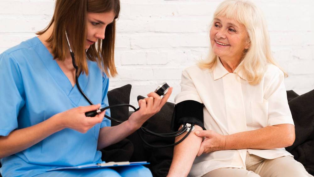 A nurse measures the blood pressure of an elderly woman in a clinical setting