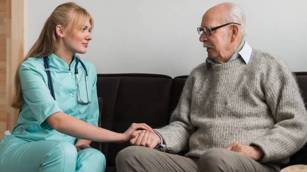 An elderly man receives comfort as a nurse holds his hand, illustrating the bond of care and support in a medical setting.