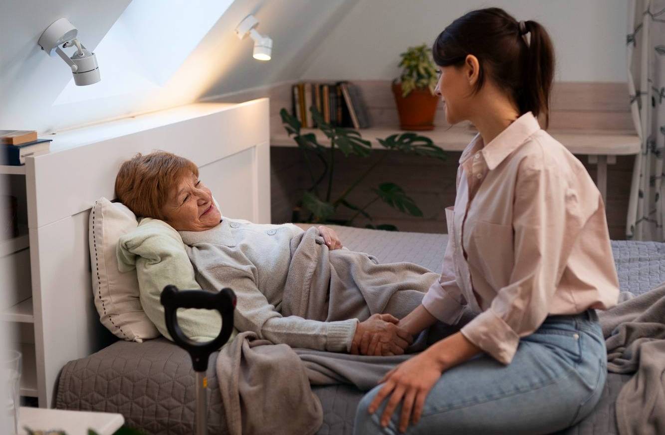 a nurse comforts an old woman in bed